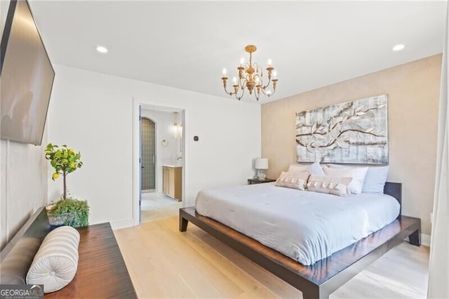 bedroom featuring a chandelier, hardwood / wood-style floors, and ensuite bathroom