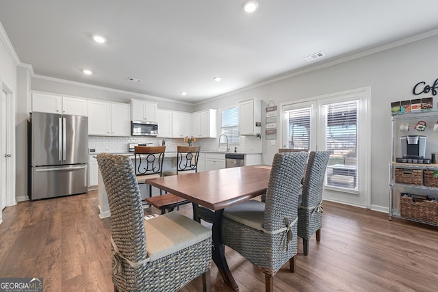 dining area with crown molding, sink, and dark wood-type flooring