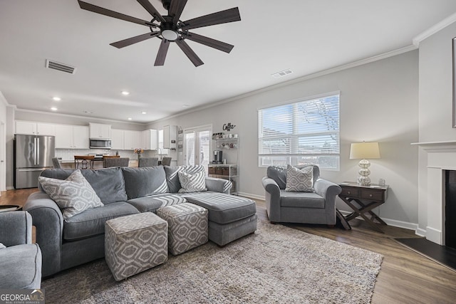 living room with hardwood / wood-style floors, ceiling fan, and crown molding