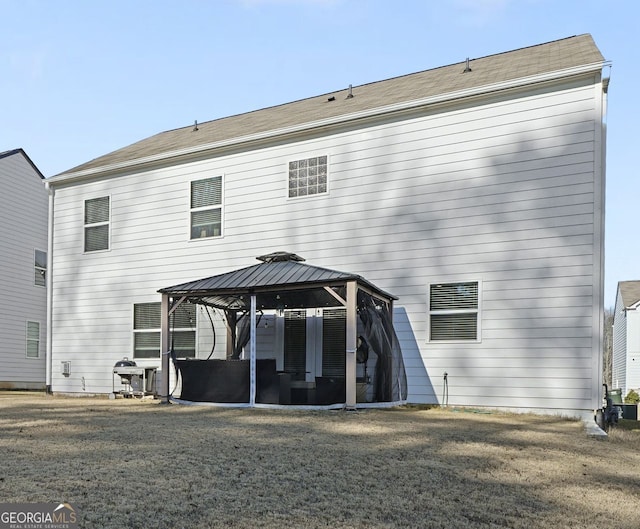 rear view of house featuring a gazebo and a yard