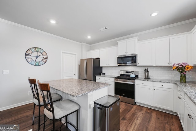 kitchen with a center island, white cabinetry, appliances with stainless steel finishes, and tasteful backsplash