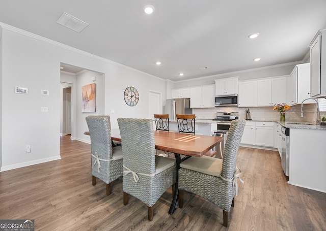 dining room featuring light hardwood / wood-style floors, sink, and crown molding