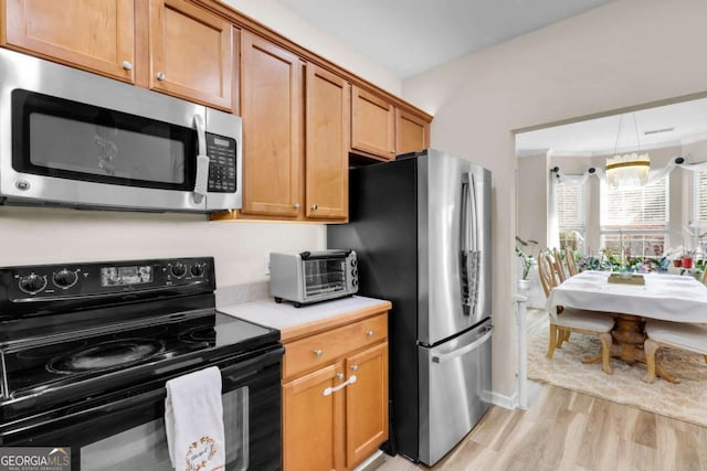 kitchen with a chandelier, light hardwood / wood-style flooring, and stainless steel appliances