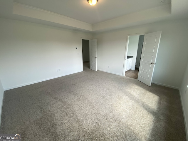 unfurnished bedroom featuring dark colored carpet and a tray ceiling