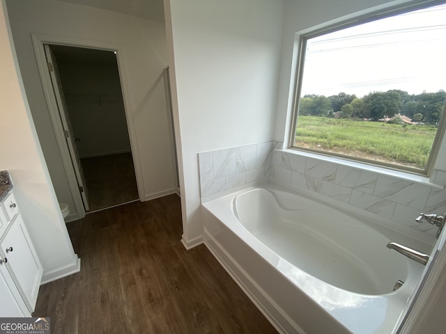 bathroom with a bathing tub, vanity, toilet, and hardwood / wood-style flooring