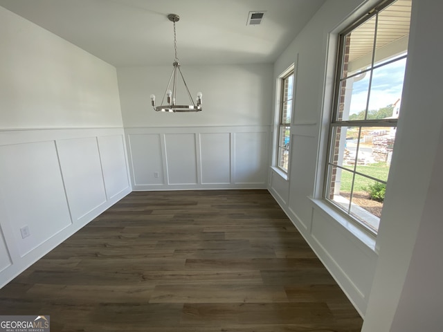 unfurnished dining area featuring dark hardwood / wood-style flooring and a chandelier