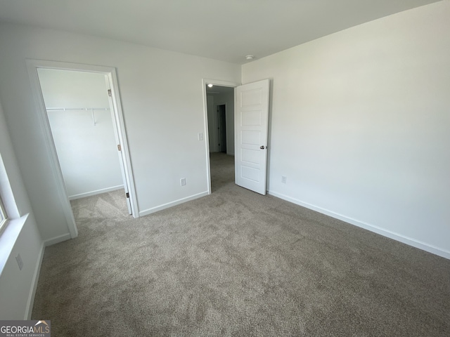 unfurnished bedroom featuring a walk in closet, light colored carpet, and a closet