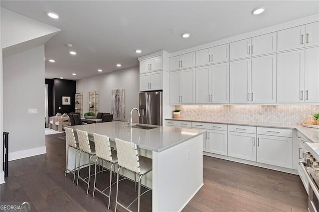 kitchen with a center island with sink, white cabinetry, a breakfast bar area, and appliances with stainless steel finishes