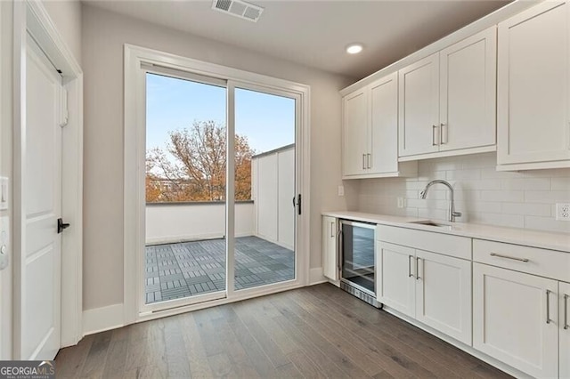 interior space with sink, decorative backsplash, dark hardwood / wood-style flooring, white cabinetry, and beverage cooler