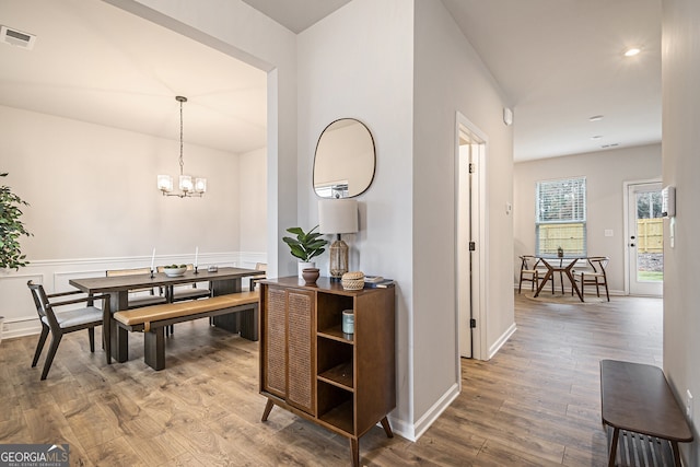 dining room with wood-type flooring and an inviting chandelier