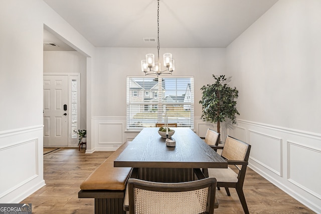 dining area featuring wood-type flooring and an inviting chandelier