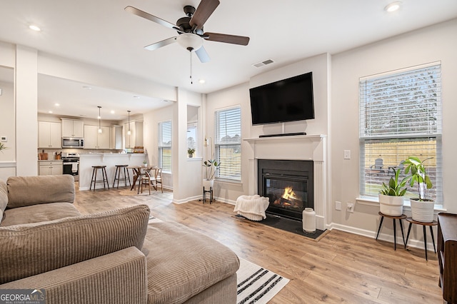 living room featuring light hardwood / wood-style flooring, plenty of natural light, and ceiling fan