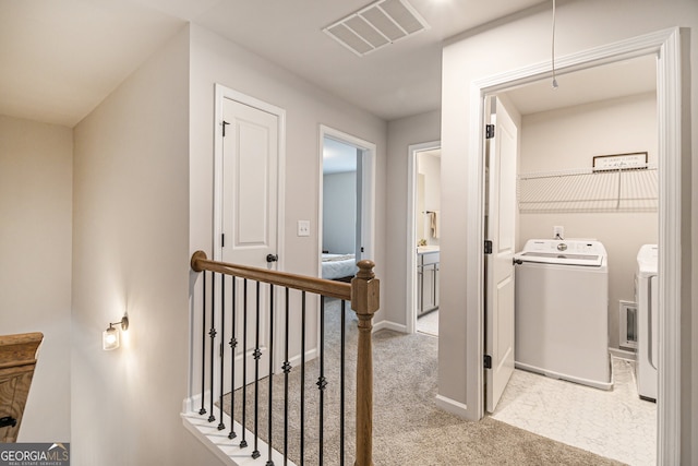 hallway with light colored carpet and independent washer and dryer