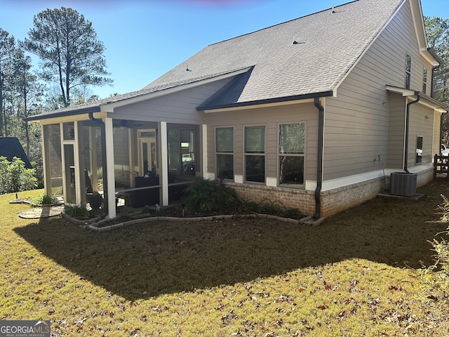 rear view of house featuring a lawn, central air condition unit, and a sunroom