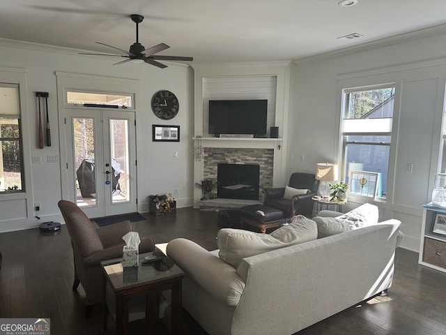 living room featuring french doors, dark hardwood / wood-style flooring, a stone fireplace, and ceiling fan