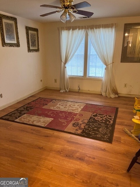 sitting room with visible vents, wood finished floors, baseboards, and ceiling fan