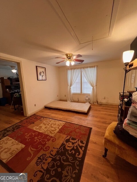 interior space with attic access, a ceiling fan, and light wood finished floors