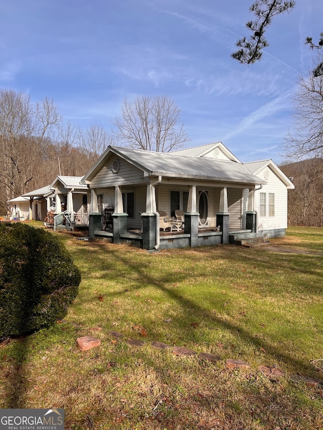 back of property with metal roof, a lawn, and a porch