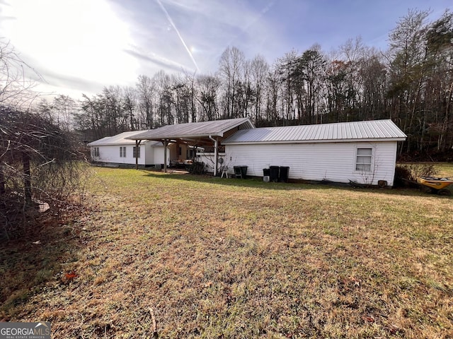 rear view of property featuring a carport, metal roof, and a yard