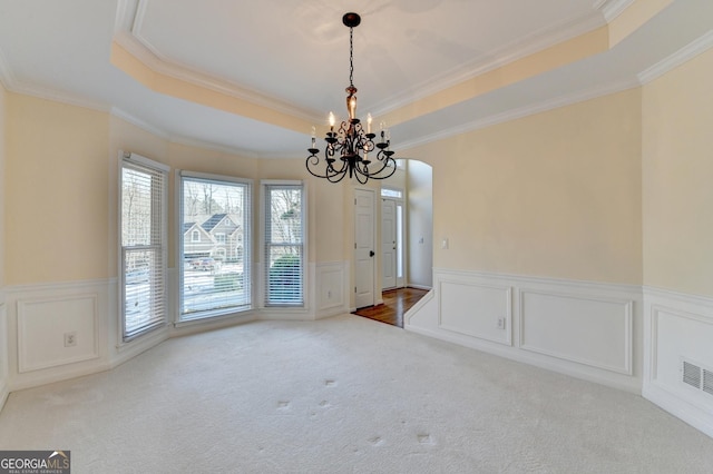 unfurnished dining area featuring a notable chandelier, light colored carpet, ornamental molding, and a tray ceiling