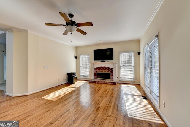 unfurnished living room with light wood-type flooring, a brick fireplace, ceiling fan, and ornamental molding