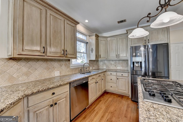 kitchen featuring pendant lighting, crown molding, sink, light hardwood / wood-style flooring, and appliances with stainless steel finishes