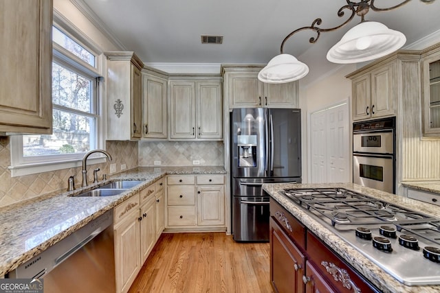 kitchen featuring light wood-type flooring, ornamental molding, stainless steel appliances, sink, and hanging light fixtures