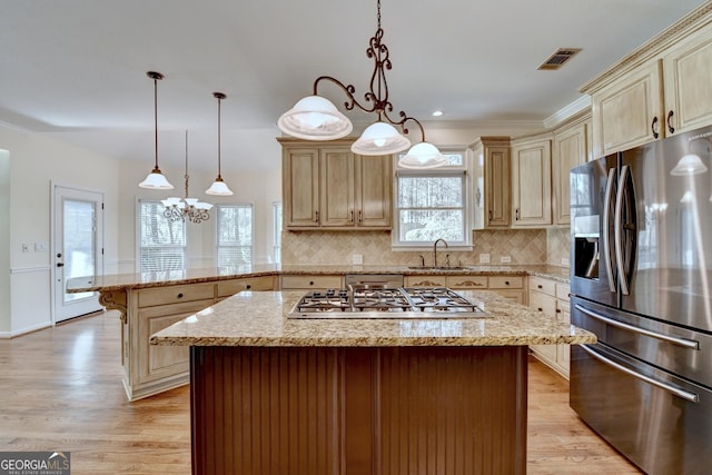 kitchen with pendant lighting, stainless steel appliances, a kitchen island, and sink