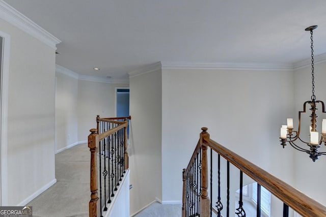 hallway with a notable chandelier, light colored carpet, and crown molding