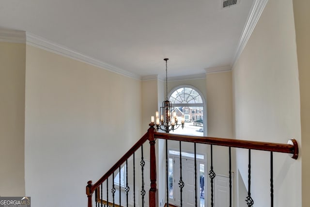 stairs with ornamental molding and a notable chandelier