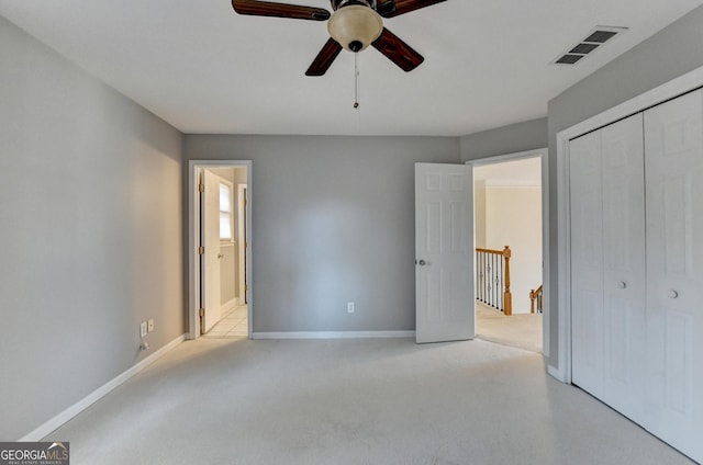 unfurnished bedroom with a closet, ceiling fan, light colored carpet, and ensuite bathroom