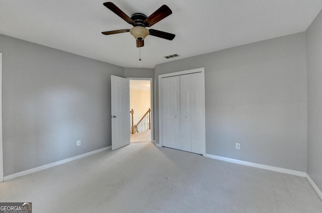 unfurnished bedroom with ceiling fan, light carpet, and a closet