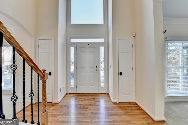 foyer entrance featuring a high ceiling, light hardwood / wood-style floors, plenty of natural light, and ornamental molding