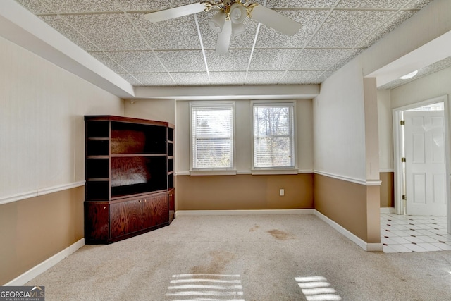 unfurnished living room featuring ceiling fan, a drop ceiling, and light carpet