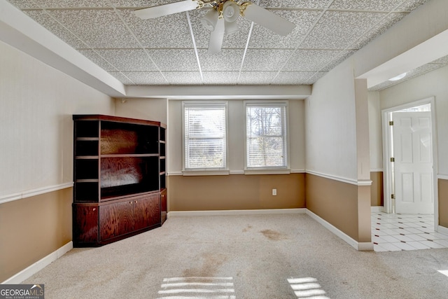 unfurnished living room featuring a paneled ceiling, light colored carpet, and ceiling fan