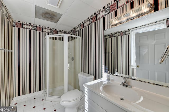 bathroom featuring vanity, toilet, an enclosed shower, and a drop ceiling