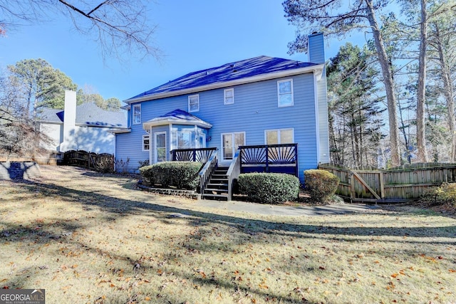 rear view of house with a lawn and a wooden deck