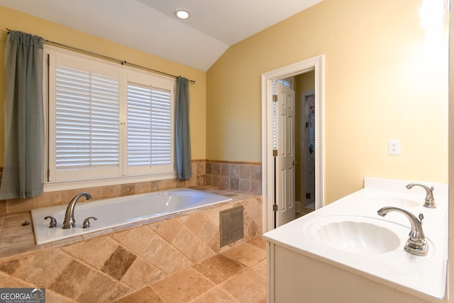 bathroom with vanity, lofted ceiling, and tiled tub