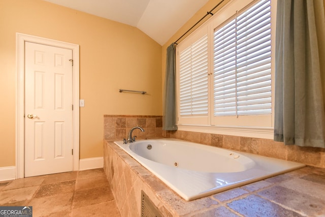 bathroom featuring tiled bath and vaulted ceiling