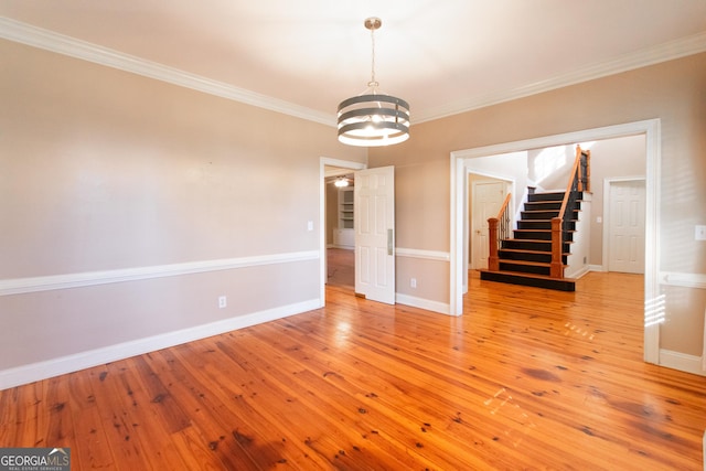 unfurnished room featuring an inviting chandelier, ornamental molding, and light wood-type flooring