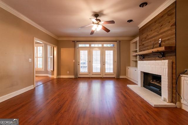 unfurnished living room featuring crown molding, ceiling fan, built in features, a fireplace, and dark hardwood / wood-style flooring