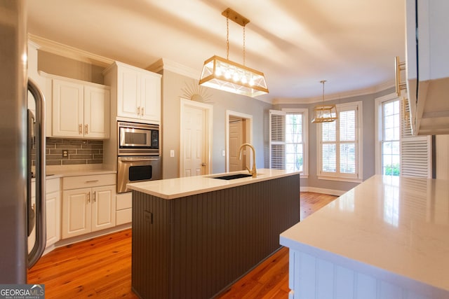 kitchen featuring white cabinetry, a kitchen island with sink, hanging light fixtures, and stainless steel appliances