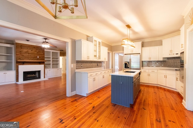 kitchen featuring decorative backsplash, white cabinetry, and an island with sink