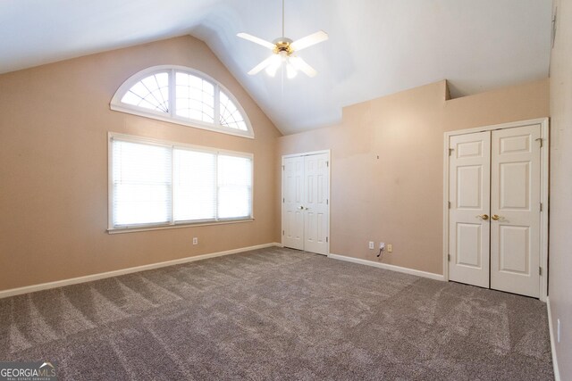 unfurnished bedroom with carpet flooring, ceiling fan, high vaulted ceiling, and two closets