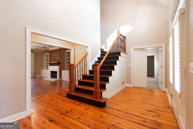 stairs with a fireplace, a high ceiling, and hardwood / wood-style flooring