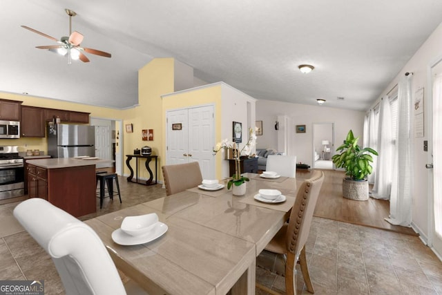 dining area featuring ceiling fan, light hardwood / wood-style floors, and vaulted ceiling