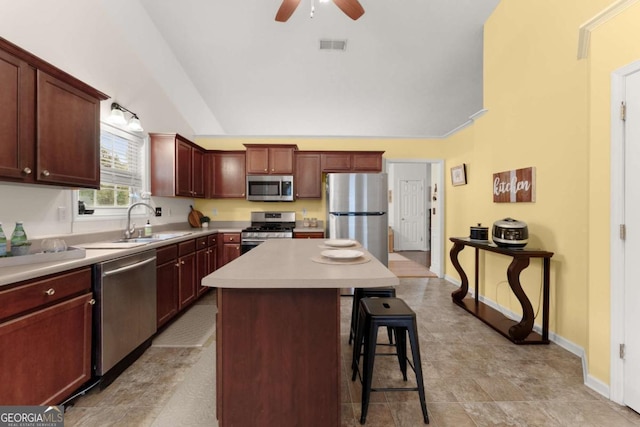 kitchen featuring a kitchen bar, appliances with stainless steel finishes, ceiling fan, sink, and a center island