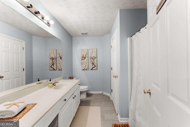 bathroom featuring vanity, a textured ceiling, and toilet