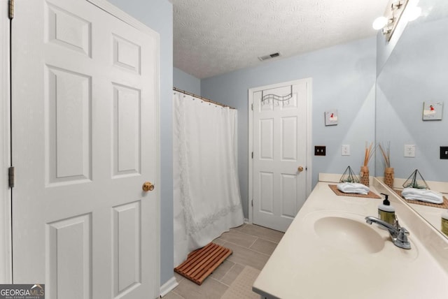 bathroom featuring vanity, shower / bath combo, a textured ceiling, and tile patterned flooring