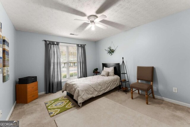 carpeted bedroom featuring a textured ceiling and ceiling fan